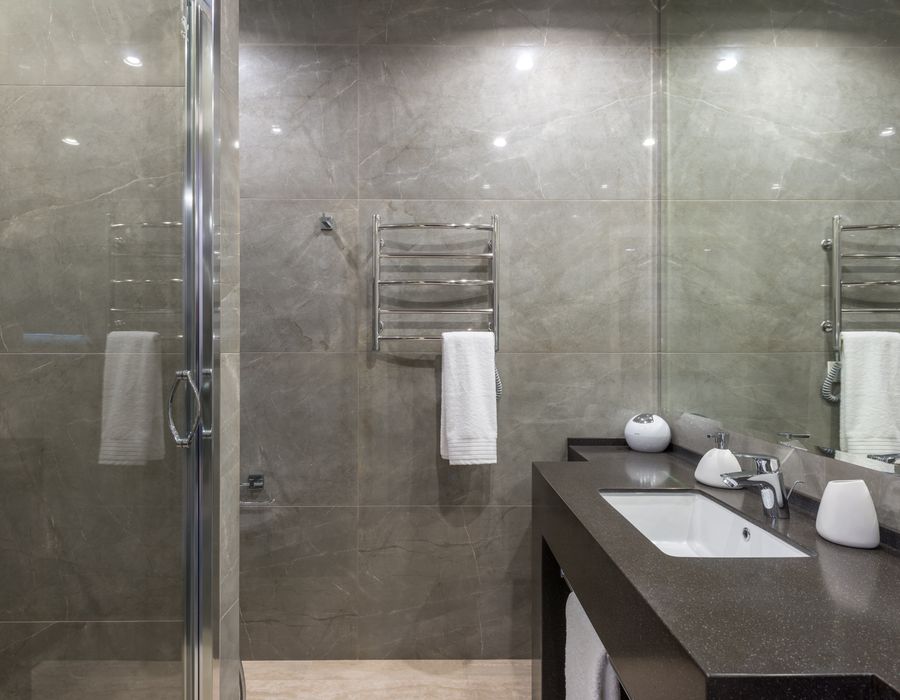 Minimalistisches Bad mit Glasdusche und glänzenden Fliesen
